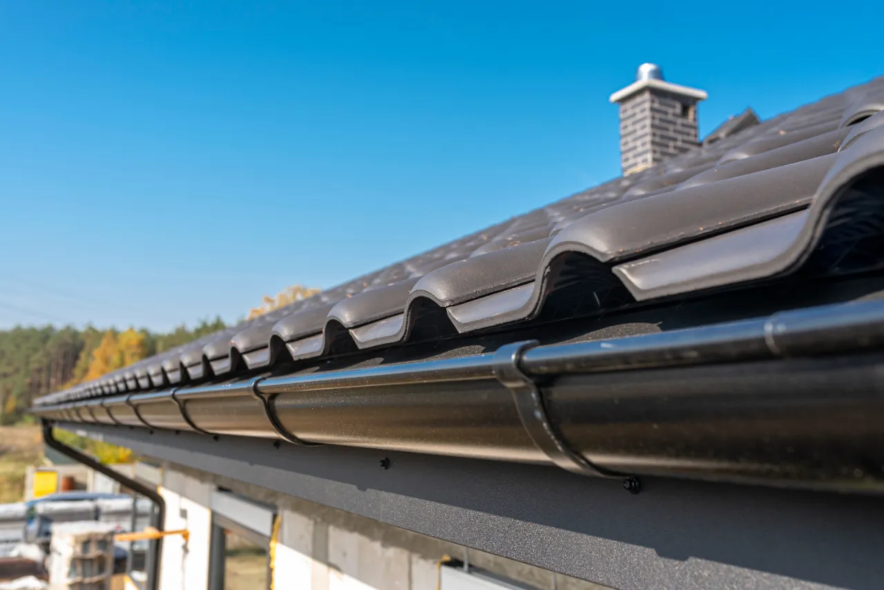 Black seamless gutter running along a tiled roof edge